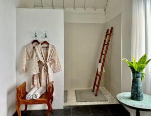 a robe hanging on a wall next to a chair at The White Villas Ubud in Ubud