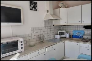 a kitchen with white cabinets and a microwave on a counter at Le plongeoir in Saint-Trojan-les-Bains