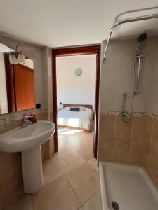 een badkamer met een wastafel, een douche en een bed bij Residenza "SINIS" in Càbras