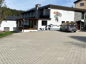 samochód zaparkowany na parkingu przed budynkiem w obiekcie La Irmania Pension w mieście Ledenitzen