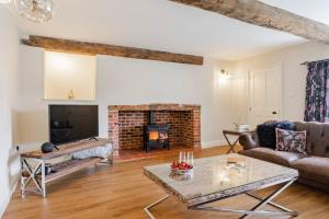 sala de estar con sofá y chimenea en Miller Retreat Stunning thatched cottage with garden and parking, en Weybourne