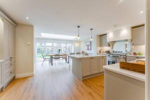 una cocina con armarios blancos y una mesa con sillas. en Miller Retreat Stunning thatched cottage with garden and parking, en Weybourne