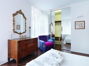 - une chambre avec un lit, une commode et un miroir dans l'établissement Villa Ella in Luxury Resort, à Gardone Riviera