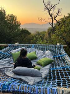 a woman sitting on a bed with pillows at JUMANJI NATURE RESORT in Hartbeespoort