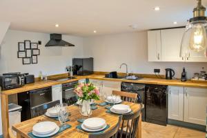 a kitchen with a wooden table with plates and flowers on it at Stainsborough Hall Holiday Cottages in Wirksworth