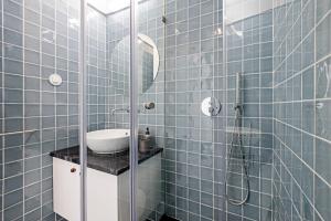 een blauwe betegelde badkamer met een wastafel en een douche bij Ceuta Studio Apartments by LovelyStay in Porto
