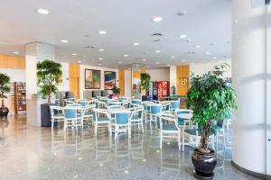 a restaurant with white chairs and a potted plant at Apartaments Condado by Marsol in Lloret de Mar
