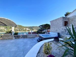 a patio with a hot tub and a table at Villa FJERA - sea view, hot tubs, terrace, BBQ in Pučišća