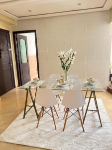 a dining room with a glass table and white chairs at Cœur de ville in Kenitra