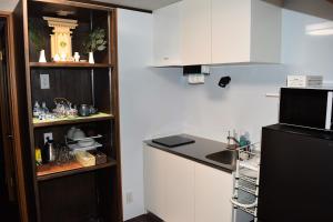 a kitchen with a black refrigerator and white cabinets at とれるの【TORERUNO】 in Takayama