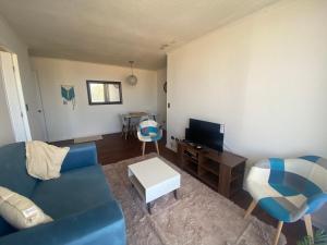 ein Wohnzimmer mit einem blauen Sofa und einem TV in der Unterkunft Apartamento boldo Curicó in Curicó