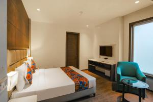 a bedroom with a bed and a desk and a television at FabHotel Hexa Chhatarpur in New Delhi