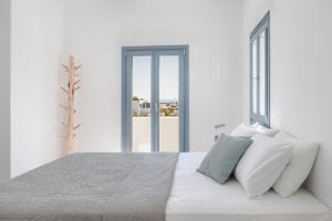 a white bedroom with a large bed with white pillows at Pebble Summer House in Kampos Paros