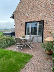 a patio with a table and chairs in front of a brick building at B&B 't Hoveke in Wingene