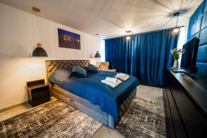 1 dormitorio con 1 cama azul y TV en Apartament P&B en Rybnik