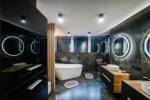 La salle de bains noire est pourvue d'une baignoire, de 2 lavabos et d'une baignoire. dans l'établissement Apartament P&B, à Rybnik