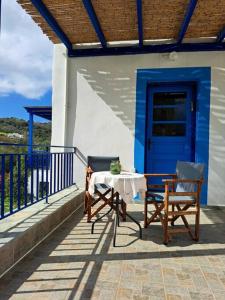 einen Tisch und zwei Stühle auf einer Veranda mit blauer Tür in der Unterkunft LA-REEF at Lakki, Leros in Lakkíon