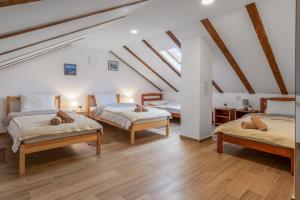 a attic room with three beds and wooden floors at SOKOL - Secret forest house in Gračac