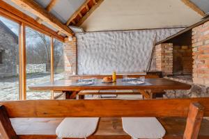 a wooden table and benches in a room with windows at SOKOL - Secret forest house in Gračac