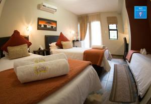 a hotel room with two beds and a window at Arista Guesthouse in Bloemfontein
