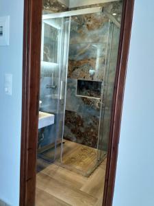 a glass shower in a bathroom with a sink at spiros maria studios in Corfu Town