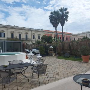 un patio con mesas y sillas frente a un edificio en Dimora Charleston Lecce parcheggio privato in loco gratis en Lecce