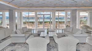 a living room with white furniture and large windows at Divani Corfu Palace in Corfu Town