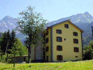 a yellow building on a hill with mountains in the background at Heidi's Guesthouse in Frenières