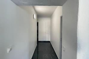 ein Flur mit weißen Wänden und schwarzem Fliesenboden in der Unterkunft RIVA BELLA villa plage in Bandol