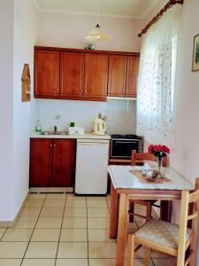 a kitchen with wooden cabinets and a table with chairs at spiros maria studios in Corfu Town