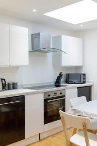 uma cozinha com armários brancos e um forno com placa de fogão em Spacious central Hove 1-bed flat em Brighton & Hove