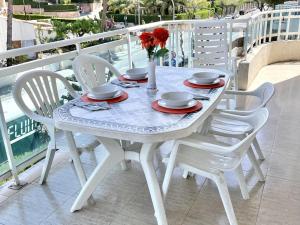 Biały stół z 4 krzesłami i waza z kwiatami w obiekcie APARTBEACH LARIMAR MUY LUMINOSO y CLIMATIZADO w Salou