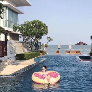 a woman riding on an inner tube in a swimming pool at The Vimanlay Beachfront Condo Retreat 3rd Floor in Cha Am