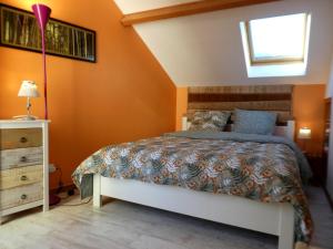 a bedroom with a bed with orange walls and a window at LA TUILIERE in Mutigny