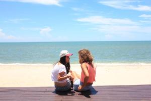 two women sitting on a pier at the beach at The Vimanlay Beachfront Condo Retreat 3rd Floor in Cha Am