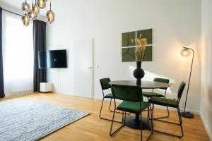 a dining room with a table and green chairs at Brand-new apartment with a breathtaking design located right near Belvedere Castle, 15 minutes from city centre in Vienna