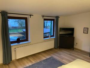a living room with two windows and a television at Haus mit wunderschönem Garten in Bad Freienwalde