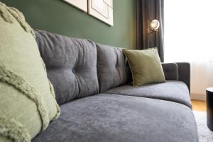 a gray couch with pillows in a living room at Brand-new apartment with a breathtaking design located right near Belvedere Castle, 15 minutes from city centre in Vienna