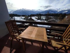 a wooden table and chairs on a balcony with mountains at Attic Gem with Unbeatable Lake Moubra View in Crans-Montana