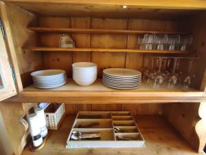 a wooden cabinet with plates and dishes in it at Attic Gem with Unbeatable Lake Moubra View in Crans-Montana