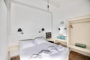 Habitación blanca con cama y espejo en Dawn Suites Santorini, en Vourvoúlos