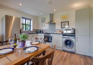 cocina con mesa de madera con sillas y lavadora en 3 Hilltop Cottages, en Stansted
