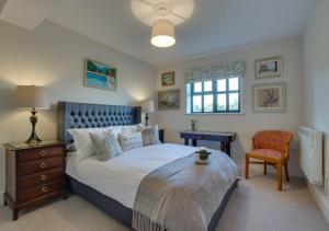 a bedroom with a large bed and a chair at 3 Hilltop Cottages in Stansted