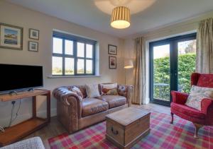 a living room with a couch and a tv at 3 Hilltop Cottages in Stansted