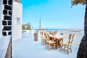 una mesa de madera y sillas en el balcón de una casa en Dawn Suites Santorini, en Vourvoúlos