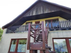 a house with a balcony with a staircase on it at Tahi Apartman in Tahitótfalu