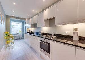 a kitchen with white cabinets and a stove top oven at Beachside Hideaway in Broadstairs