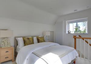 a bedroom with a bed with white sheets and a window at Beech Cottage at Fir House in Cranbrook