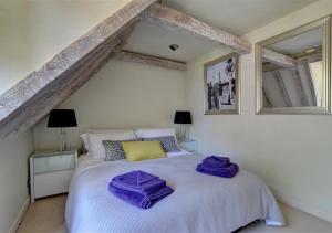 um quarto com uma cama branca e toalhas roxas em 3 Stable Mews em Royal Tunbridge Wells