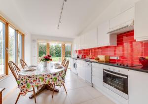 uma cozinha com mesa, cadeiras e azulejos vermelhos em Apple Barn em Lyminge